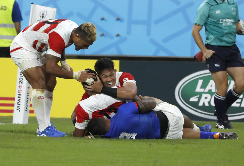 Japan's Timothy Lafaele is congratulated by teammates after scoring a try during the Rugby World Cup Pool A game at City of Toyota Stadium between Japan and Samoa in Tokyo City, Japan, Saturday, Oct. 5, 2019. (AP Photo/Shuji Kajiyama)