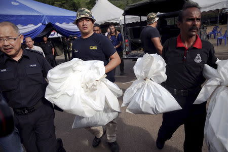 Forensic policemen carry body bags with human remains found at the site of human trafficking camps in the jungle close the Thailand border after they brought them to a police camp near Wang Kelian in northern Malaysia in this May 25, 2015 file photo. REUTERS/Damir Sagolj/Files