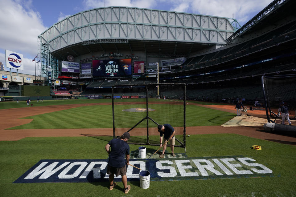 Stadium workers paint the logo on the field Monday, Oct. 25, 2021, in Houston, in preparation for Game 1 of baseball's World Series tomorrow. (AP Photo/David J. Phillip)