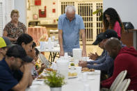 Daniel Monduy leads a group of newly arrived migrants in prayer before dinner at the Iglesia Rescate, Tuesday, Feb. 21, 2023, in Hialeah, Fla. The church provides the migrants a place to sleep in their school classrooms and offers portable showers and toilets for them to use. (AP Photo/Marta Lavandier)