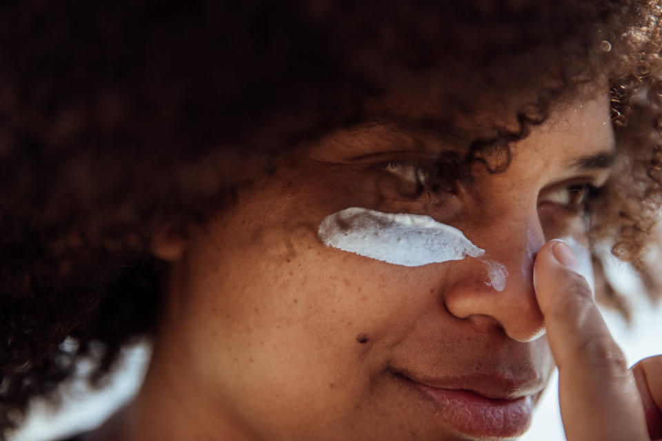 Close-up of a person gently applying sunscreen to their face, focusing on the area under the eye