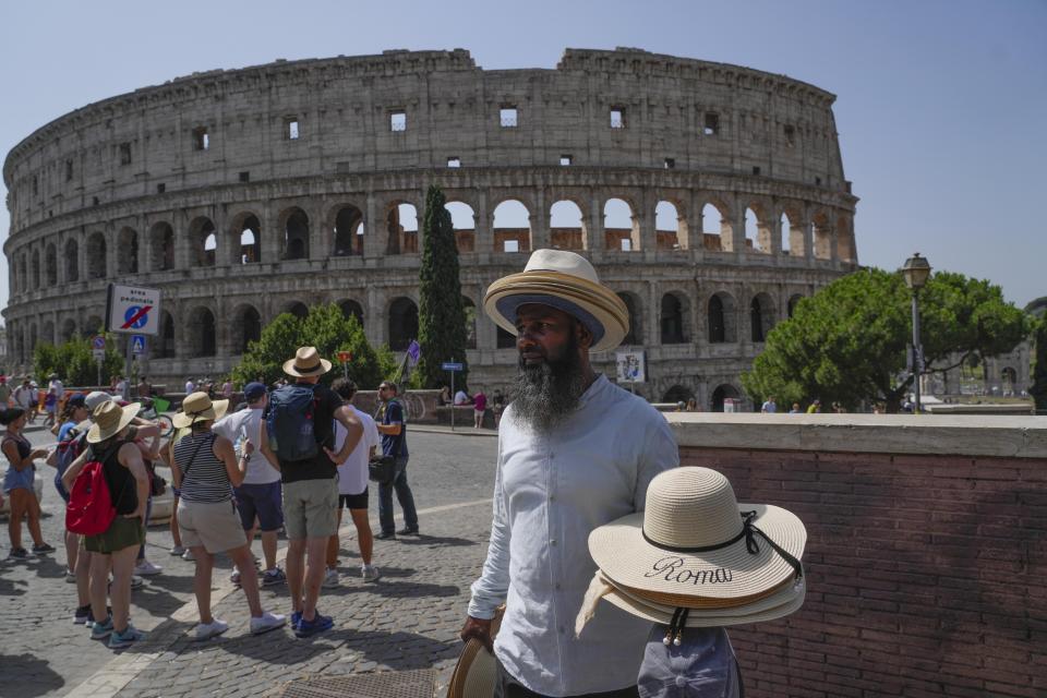 A street vendor walks with hats in front of the Colosseum in Rome, Monday, July 17, 2023. Tourist flock to the eternal city while scorching temperatures grip central Italy with Rome at the top of the red alert list as one of the hottest cities in the country. (AP Photo/Gregorio Borgia)