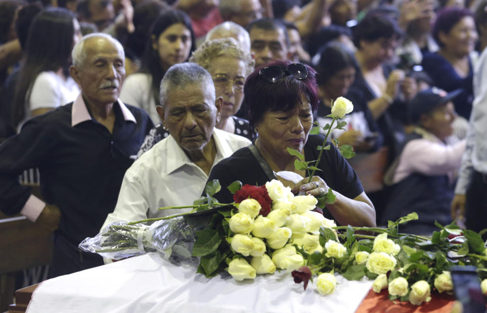 A supporter of Peru's late President Alan Garcia puts a flower on his coffin on the second day of his wake at his party's headquarters in Lima, Peru, Thursday, April 18, 2019. Garcia shot himself in the head and died Wednesday as officers waited to arrest him in a massive graft probe that has put the country's most prominent politicians behind bars and provoked a reckoning over corruption. (AP Photo/Martin Mejia)