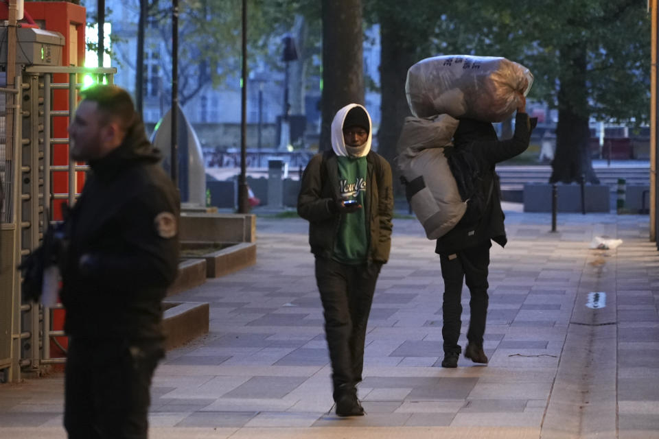 Migrants leave a makeshift camp after being evicted by police officers, early Tuesday April 23, 2024 in Paris. French police officers have evicted migrants from a makeshift camp in Paris a few steps away from the Seine River, as similar operations have been carried out by authorities ahead of the Olympics. (AP Photo/Nicolas Garriga)