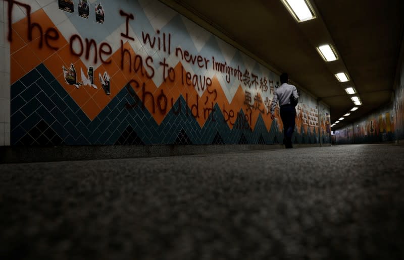 A man walks past anti-government graffiti at a underground passage in Hong Kong