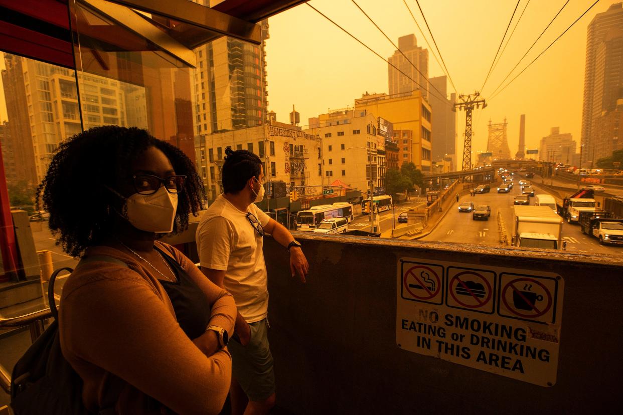 People wear masks as they wait for the tramway to Roosevelt Island as smoke from Canadian wildfires casts a haze over the area on June 7, 2023 in New York City. Air pollution alerts were issued across the United States due to smoke from wildfires that have been burning in Canada for weeks.