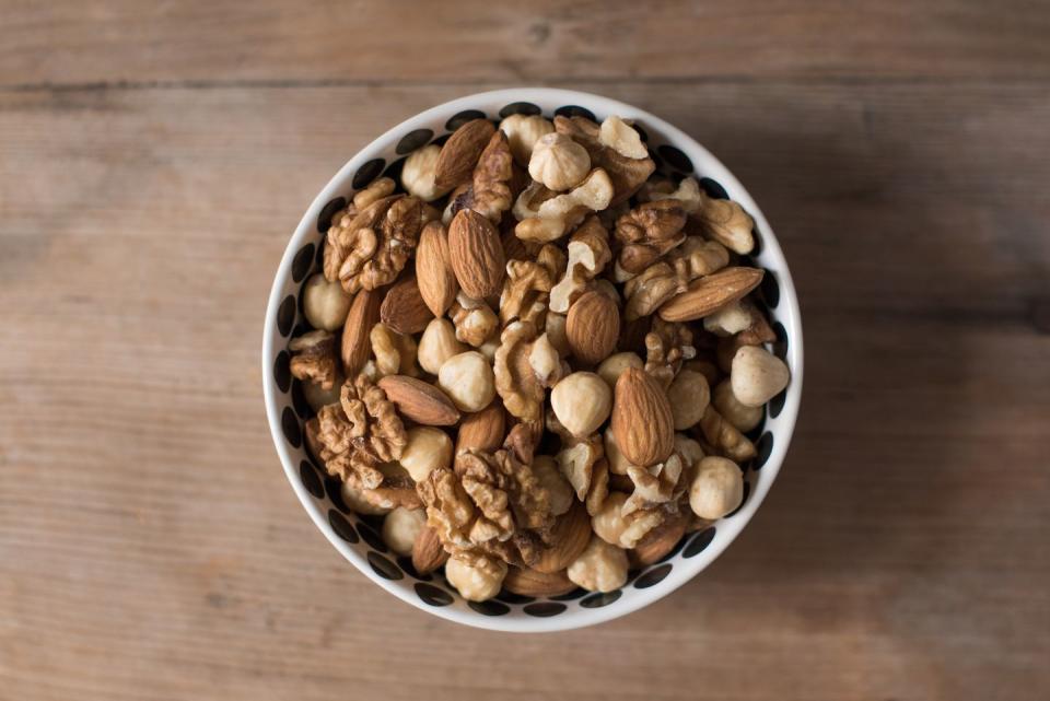 walnuts, almonds and hazelnuts in a bowl on wooden table