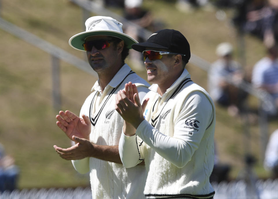 New Zealand's Colin de Grandhomme, left, and teammate Henry Nichols applaud their teammates after dismissing India for 191 runs in their second innings during the first cricket test between India and New Zealand at the Basin Reserve in Wellington, New Zealand, Monday, Feb. 24, 2020. New Zealand defeated India by ten wickets. (AP Photo/Ross Setford)