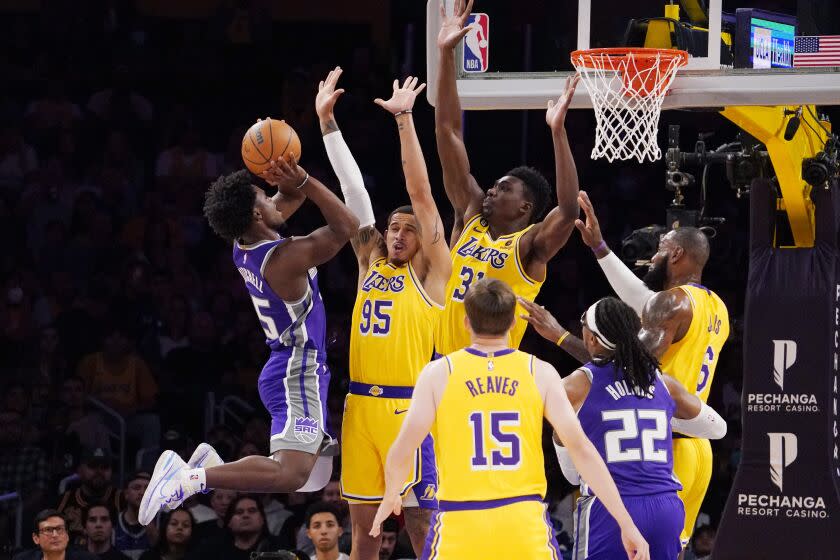 Sacramento Kings guard Davion Mitchell, left, shoots as Los Angeles Lakers forward Juan Toscano-Anderson.
