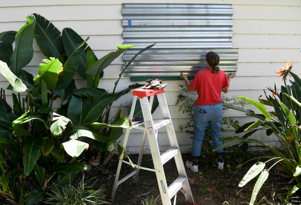 Martha Marzluff works to install shutters on her home in Rockledge in 2020.