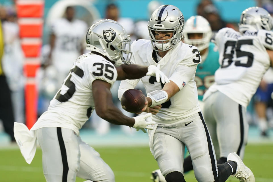 Las Vegas Raiders quarterback Jarrett Stidham (3) hands the ball to running back Zamir White (35) during the first half of a NFL preseason football game against the Miami Dolphins, Saturday, August 20, 2022, in Miami Gardens, Fla. (AP Photo/Wilfredo Lee)