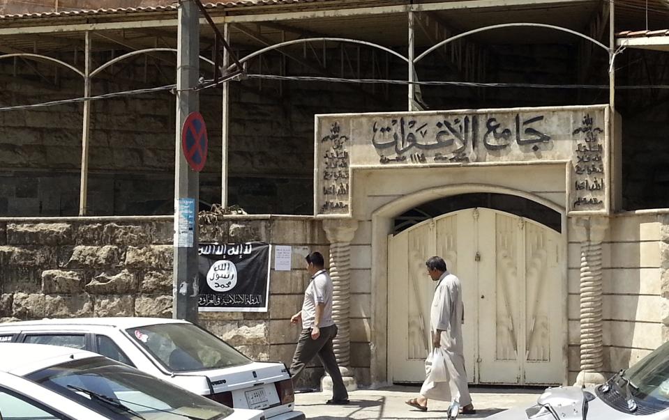 People walk past a banner (in black and white) belonging to the Islamic State in Iraq and the Levant (ISIL) in the city of Mosul, June 28, 2014. Since early June, ISIL militants have overrun most majority Sunni Muslim areas in the north and west of Iraq, capturing the biggest northern city Mosul and late dictator Saddam Hussein's hometown of Tikrit. The banner reads, "There is no God but God, and Mohammad is his messenger." REUTERS/Stringer (IRAQ - Tags: CIVIL UNREST POLITICS)