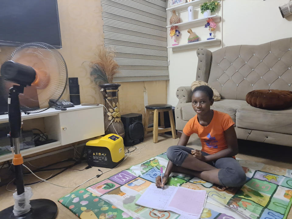 17 year old Bridget Mosanya studies for her senior school certificate exams using a solar inverter at her family home in Karu, a district of Abuja, Nigeria, Saturday June 17, 2023. Nigeria's removal of a subsidy that helped reduce the price of gasoline has increased costs for people already struggling with high inflation. But it also potentially accelerates progress toward reducing emissions in Africa's largest economy. (AP Photo/Taiwo Adebayo)