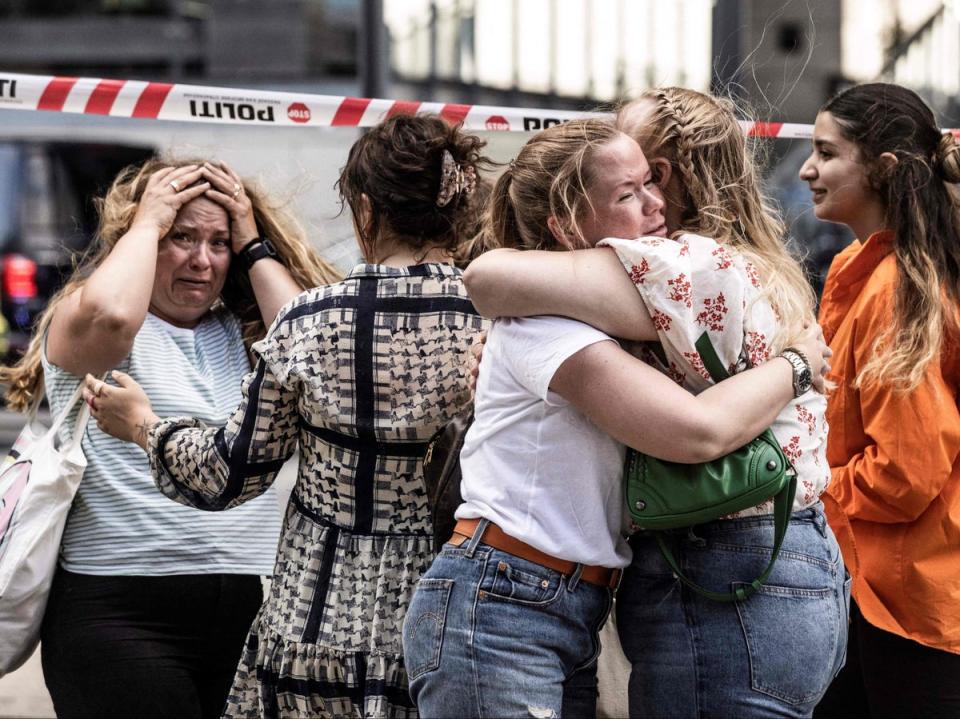People hug each other outside the Fields shopping mall, where a gunman killed three people and wounded several others (Ritzau Scanpix/AFP via Getty Images)