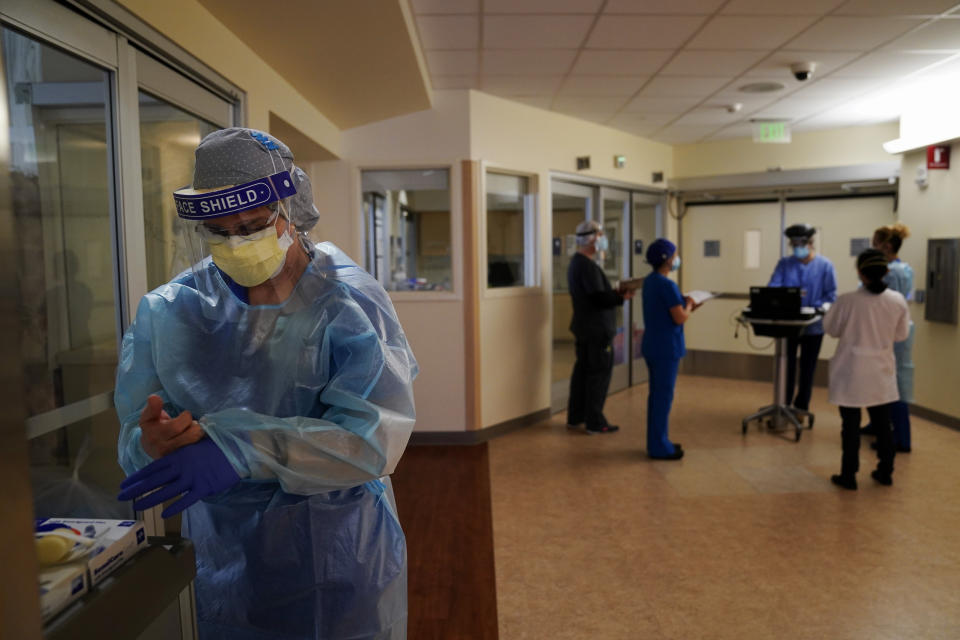 Registered nurse Merri Lynn Anderson puts on her PPE to check on her patient in a COVID-19 unit at St. Joseph Hospital in Orange, Calif., Thursday, Jan. 7, 2021. California health authorities reported Thursday a record two-day total of 1,042 coronavirus deaths as many hospitals strain under unprecedented caseloads. The state's hospitals are trying to prepare for the possibility that they may have to ration care for lack of staff and beds — and hoping they don't have to make that choice. (AP Photo/Jae C. Hong)