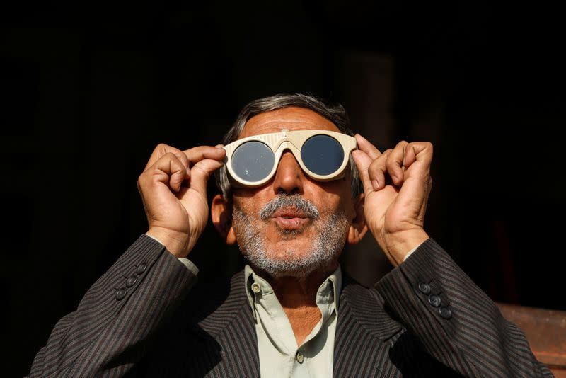 A man uses a pair of welder glasses to observe a solar eclipse in Peshawar