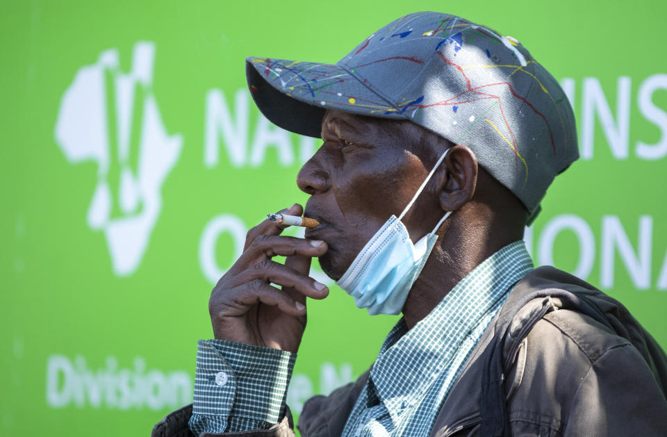 FILE — In this Tuesday, Aug. 25, 2020 file photo a man smokes a cigarette whist during protest against staff shortages and the lack of personal protective equipment outside the National Health Laboratory Services in Johannesburg, South Africa, South African Health Minister, Zwerli Mkhize announced Monday, Oct. 19 2020 that he and his wife have tested positive for COVID-19, warning of a possible resurgence of the disease in the country. (AP Photo/Themba Hadebe/File)