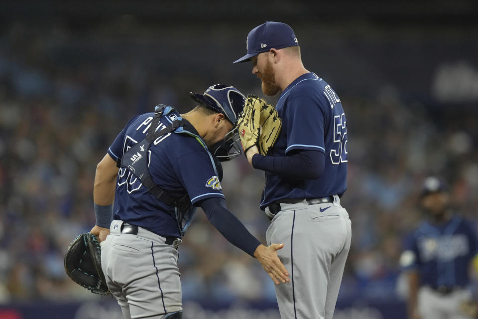 Tampa Bay Rays relief pitcher Zack Littell (52) is encouraged by Rene Pinto during a mound visit in the third inning of the team's baseball game against the Toronto Blue Jays on Friday, Sept. 29, 2023, in Toronto. (Chris Young/The Canadian Press via AP)