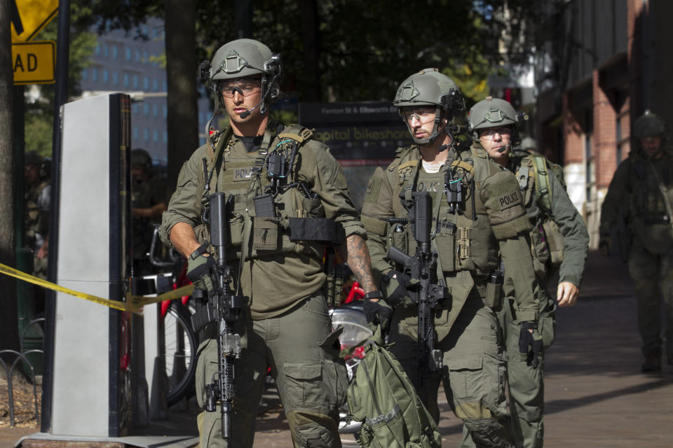 Montgomery police officers in tactical gear exit a parking garage where a police officer was shot, in downtown Silver Spring, Md., Monday, Oct. 14, 2019. Police in Montgomery County, Maryland, said they were searching for at least one person after an officer was found shot in a parking garage in downtown Silver Spring on Monday. (AP Photo/Jose Luis Magana)