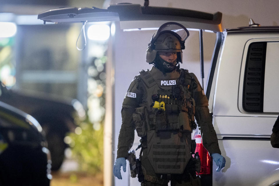 A special forces officer guards the road in front of a house that is searched through by police in Hanau, Germany, Thursday, Feb. 20, 2020. Eight people were killed in shootings in and outside two hookah lounges in a southwestern German city late Wednesday, and authorities were searching for the perpetrators. (AP Photo/Michael Probst)