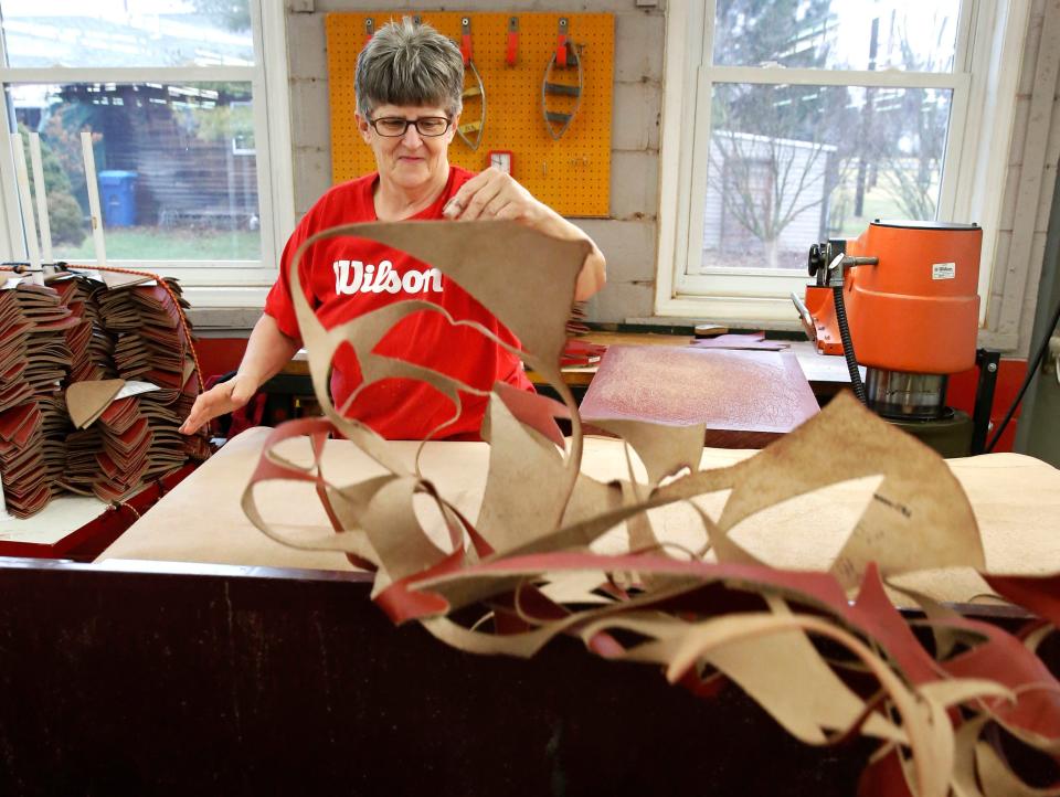 Wilson Sporting Goods worker Michelle Burkett throws excess leather from the Horween Leather Co. factory after cutting quarter panels for an NFL football in Ada, Ohio.