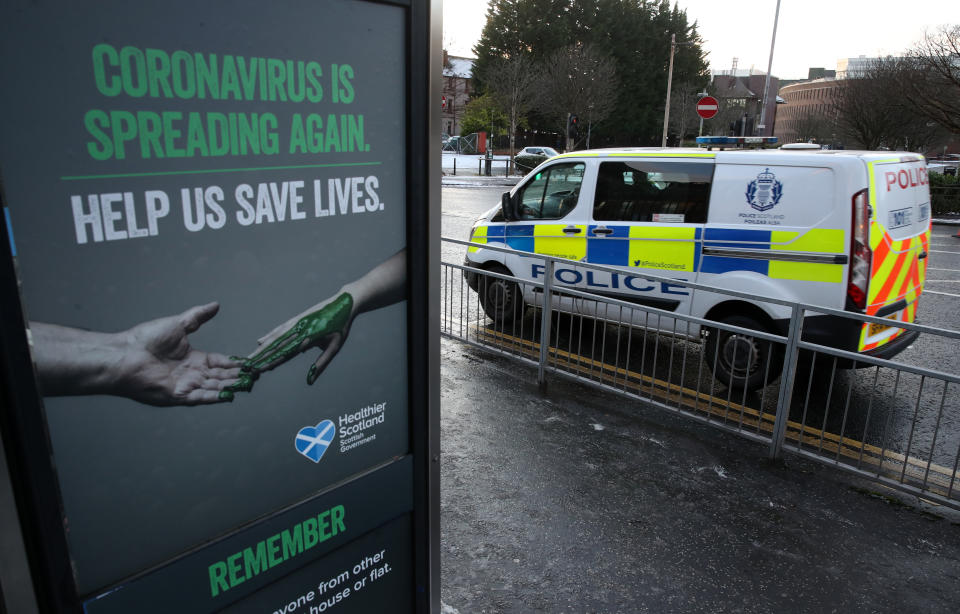 A police vehicles passes a Coronavirus related poster on a phone box outside Glasgow Royal Infirmary after severe lockdown restrictions were announced for December and January with all of the country moving into the highest level of lockdown from Boxing Day. (Photo by Andrew Milligan/PA Images via Getty Images)