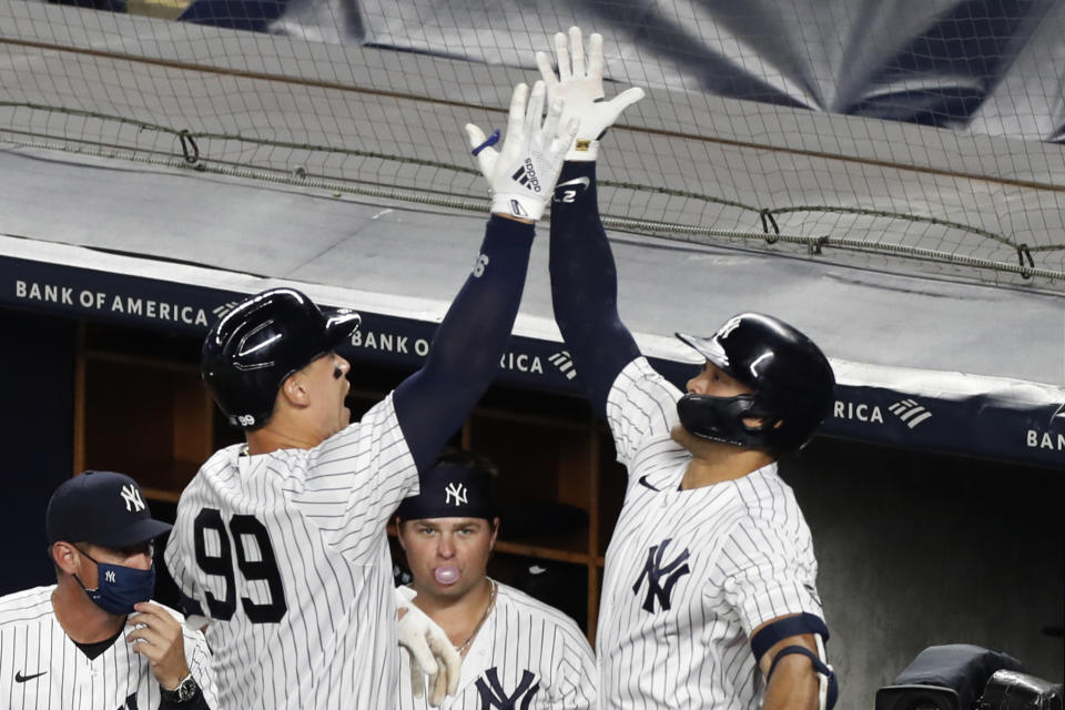 New York Yankees' Aaron Judge (99) celebrates with Giancarlo Stanton after hitting a two-run, home run in the eighth inning of a baseball game against the Boston Red Sox, Sunday, Aug. 2, 2020, at Yankee Stadium in New York. First baseman Luke Voit, blows a bubble as he watches the two celebrate. (AP Photo/Kathy Willens)