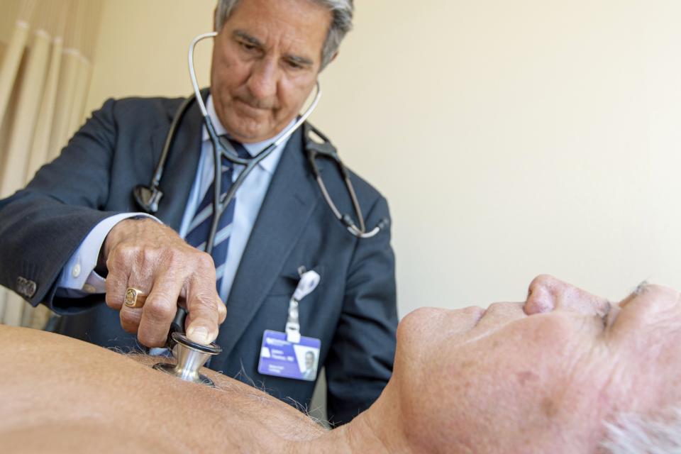 In this Monday, July 8, 2019 photo, James Thomas, a cardiologist at Northwestern Hospital in Chicago examines Dennis Calling, a retired Chicago inspector. With medical advances and competing devices over the past few decades, "the old stethoscope is kind of falling on hard times in terms of rigorous training," says Thomas. "Some recent studies have shown that graduates in internal medicine and emergency medicine may miss as many of half of (heart) murmurs using a stethoscope."(AP Photo/Amr Alfiky)