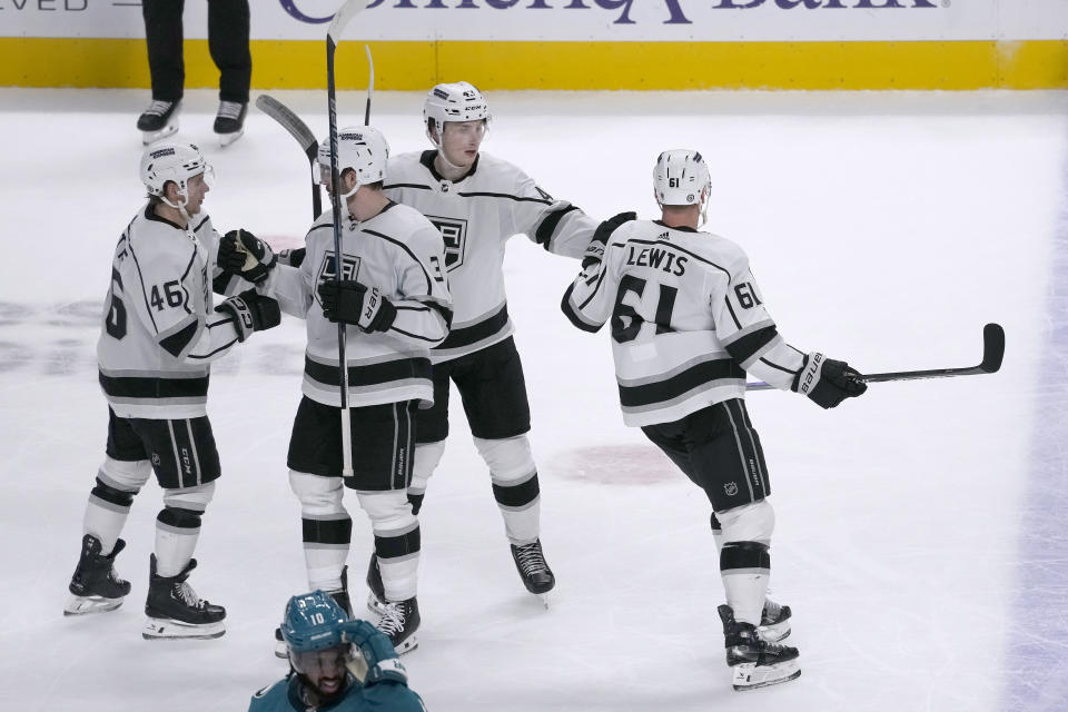 Los Angeles Kings center Blake Lizotte (46), defenseman Matt Roy (3) and defenseman Jacob Moverare (43) celebrate after center Trevor Lewis (61) scored an empty-net goal against the San Jose Sharks during the third period of an NHL hockey game in San Jose, Calif., Tuesday, Dec. 19, 2023. (AP Photo/Jeff Chiu)