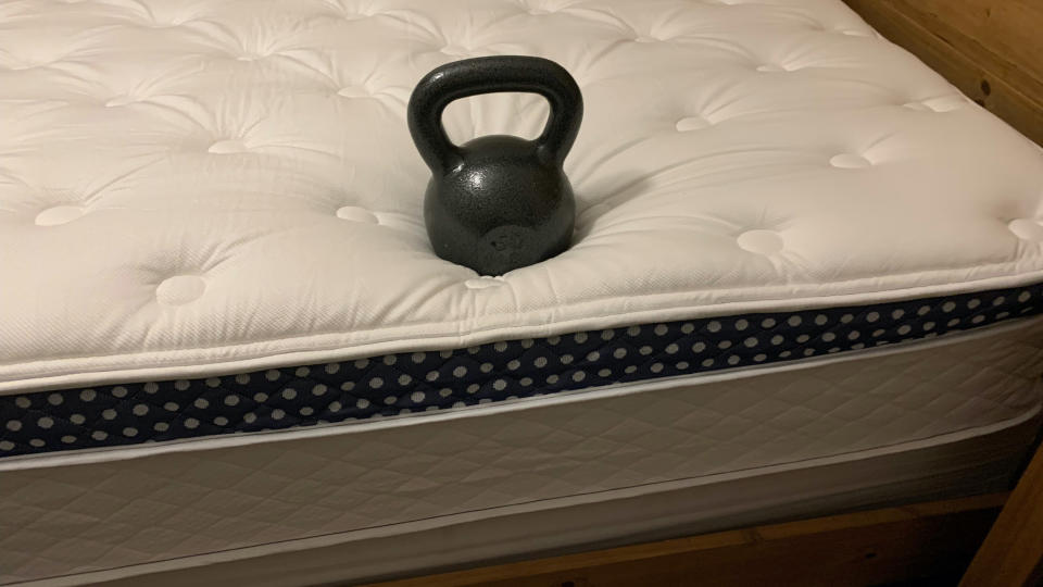 Image shows a black heavy weight placed on the edge of the WinkBed Mattress during an edge support test