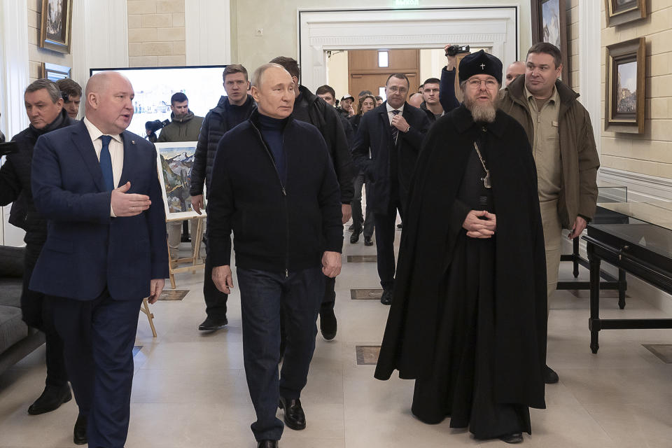 El presidente ruso, Vladímir Putin (centro) y el gobernador de Sevastópol, Mijaíl Razvozhayev (izquierda) y el metropolitano de Pskov y Porjov, Tijon Shevkunov (derecha) visitan el centro de Arte y Estética Infantil en Sevastópol, Crimea, el sábado 18 de marzo de 2023. (Sputnik, Foto de pool del Servicio de Prensa del Kremlin vía AP)