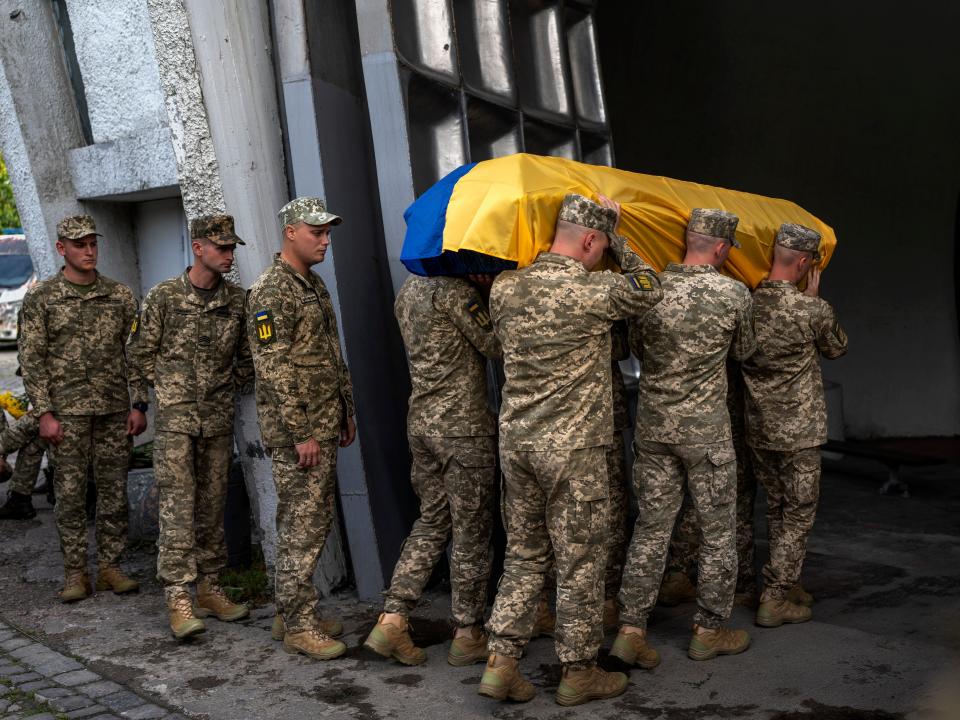 Servicemen carry the coffin of Olga Simonova, 34, a Russian woman who was killed in the Donetsk region while fighting on Ukraine's side in the war with her native country, in a crematorium in Kyiv, Ukraine, Saturday, Sept. 17, 2022.