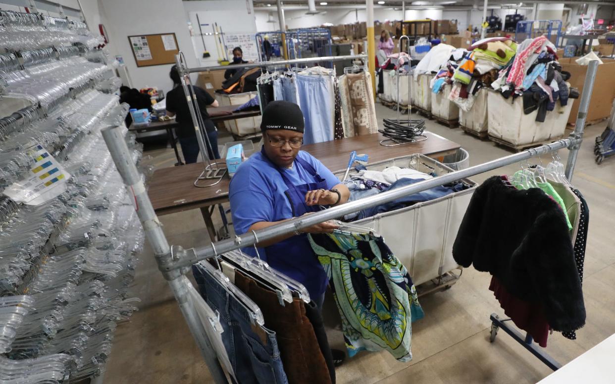 Ella Miles, a wares processor at the Goodwill Store on Waterloo Road, puts clothing items on hangers as she prepares them to go out for sale on April 26 in Akron.