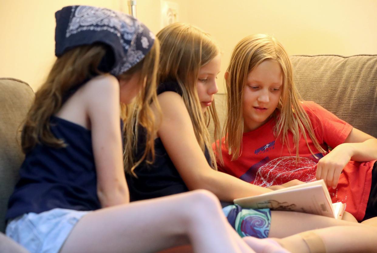 High Point Elementary School students (from left) Charlotte McCullough, Meredith Sell and Everly Hannah, all 9, look through the pages of Kate DiCamillo's "Flora & Ulysses" book during a book club meeting June 23 in Gahanna. The club was started by a group of students from High Point as a way to stay in contact during the pandemic.