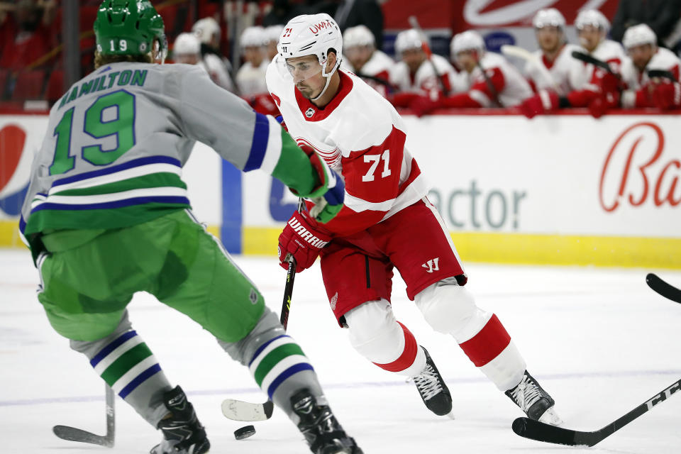 Detroit Red Wings' Dylan Larkin (71) avoids the challenge of Carolina Hurricanes' Dougie Hamilton (19) during the first period of an NHL hockey game in Raleigh, N.C., Saturday, April 10, 2021. (AP Photo/Karl B DeBlaker)