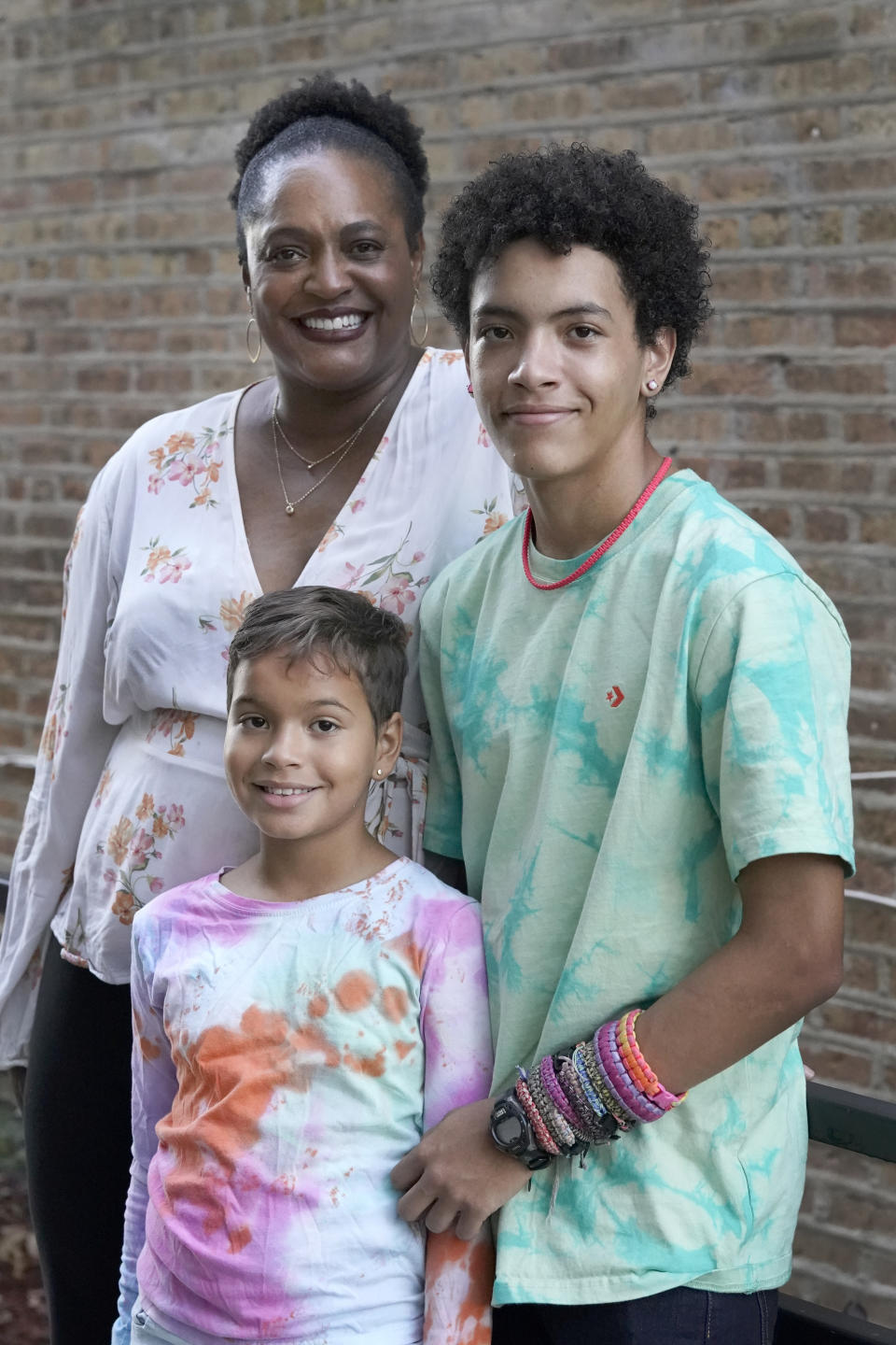 Marla Williams, left, her daughter Mariella Fallon, center, and son Miles Fallon, stand for portrait outside their Chicago home Wednesday, Oct. 12, 2022. Williams initially supported the Chicago Public Schools decision to instruct students online during the fall of 2020. Williams, a single mother, has asthma, as do her two children. While she was working, she enlisted her father, a retired teacher, to supervise her children’s studies. (AP Photo/Charles Rex Arbogast)