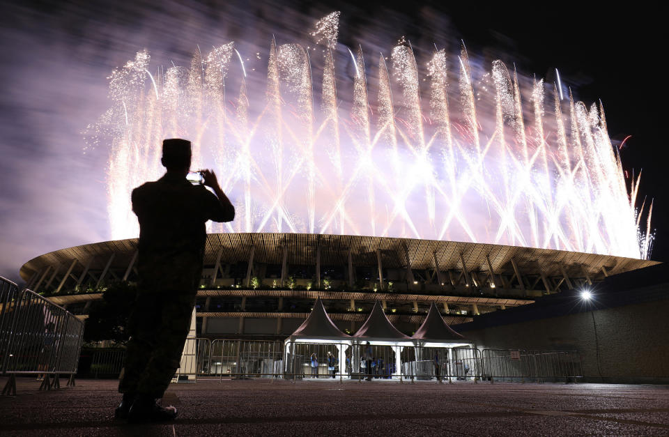 <p>A man takes pictures of the fireworks lighting up the sky over the Olympic Stadium during the opening ceremony of the Tokyo 2020 Olympic Games. (Photo by STR/JIJI PRESS/AFP via Getty Images)</p> 