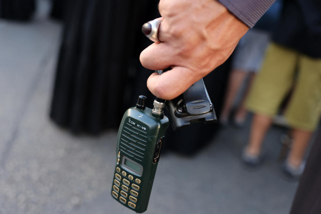 A man's hand holds a walkie-talkie with the battery removed.