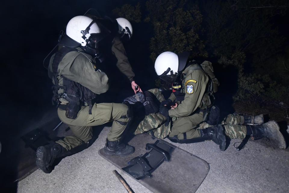 Riot police detain a protester during a rally in Karava near the area where the government plans to build a new migrant detention center, on the northeastern Aegean island of Lesbos, Greece, Tuesday, Feb. 25, 2020. Riot police and residents clashed for several hours on the Greek islands of Lesbos and Chios Tuesday, as protesters tried to prevent authorities from bringing excavating machines from the mainland to build new migrant detention camps. (AP Photo/Michael Varaklas)