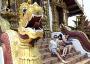 In this March 30, 2014 photo, Chinese tourists pose for a photograph at a Buddhist temple in Chiang Mai province, northern Thailand. The bucolic, once laid-back, campus of one of Thailand’s top universities seems to be under a security clampdown these days. Not against a terrorist threat, but Chinese tourists, thousands of them, who have clambered aboard student buses, eaten in cafeterias, sneaked into classes to attend lectures and even pitched a tent by a picturesque lake. Now visitors are restricted to entering through a single gate manned by Mandarin-speaking volunteers who direct Chinese tourists to a line of vehicles for guided tours. (AP Photo/Apichart Weerawong)