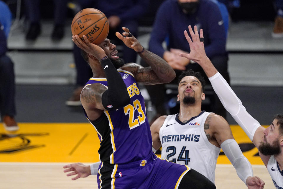 Los Angeles Lakers forward LeBron James, left, shoots as Memphis Grizzlies guard Dillon Brooks, center, and center Jonas Valanciunas defend during the first half of an NBA basketball game Friday, Feb. 12, 2021, in Los Angeles. (AP Photo/Mark J. Terrill)