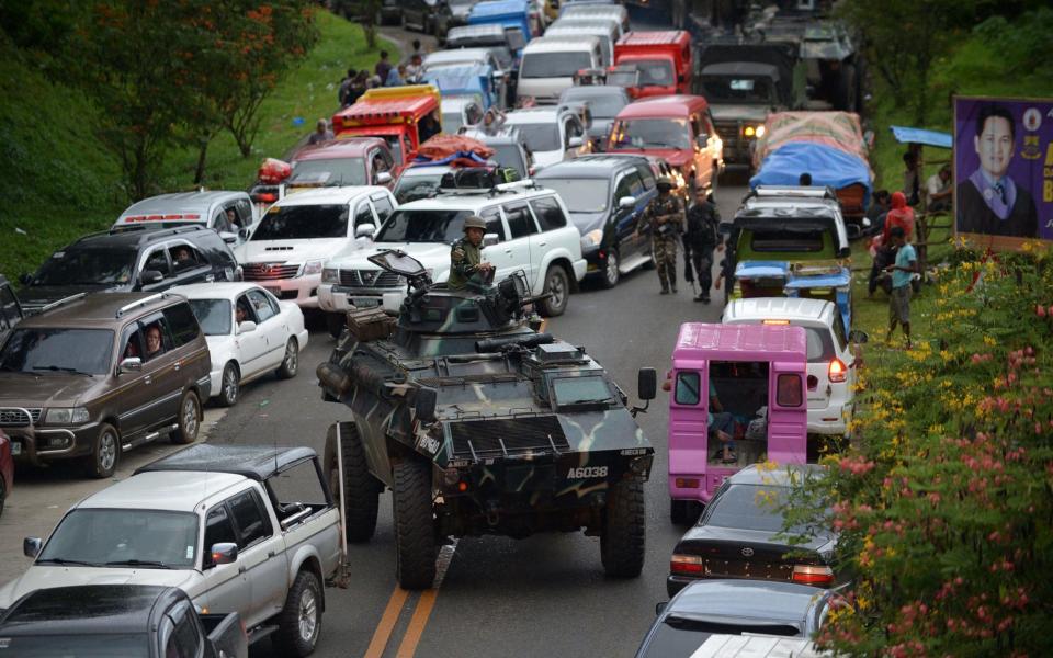 An armored personnel carrier moves amongst stuck vehicles of residents fleeing Marawi City - AFP