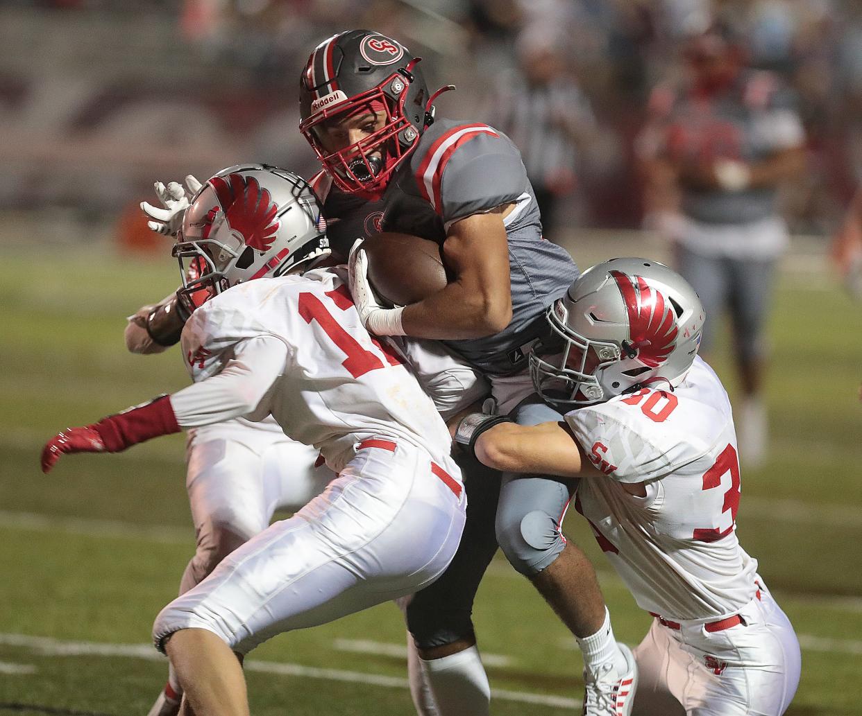 Canton South's Tavon Castle is brought down in the second half by Sandy Valley's Troy Snyder, 11, Lukas Gilland ,17, and Jack Murphy, 30, at Canton South, Friday, September 2, 2022.