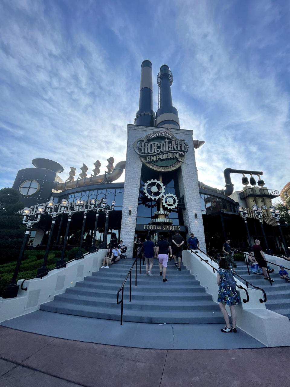 A photo of a large building with mechanical wheels around it and people on the steps