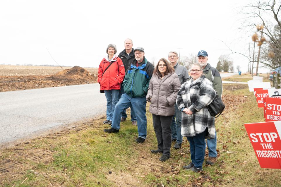 Marshall Township residents (L-R) Diane Kowalske, Glenn Kowalske, Fred Chapman, Dale Borders, Joan Chapman, Mick Woods and Marshall resident Laura Bartlett stand in front of homes along C Drive North across the street from the Megasite on Thursday, Feb. 16, 2023.
