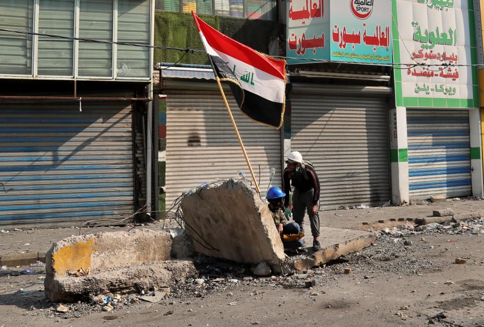 Anti-government protesters take cover during clashes with security forces on Rasheed Street, Baghdad, Iraq, Tuesday, Nov. 26, 2019. (AP Photo/Khalid Mohammed)