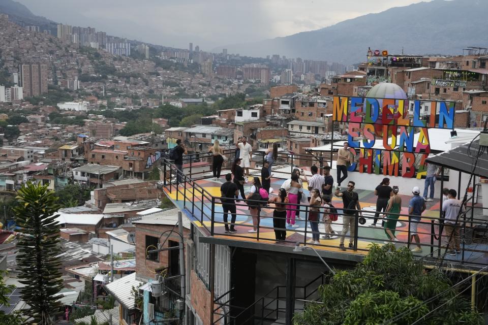 Turistas se toman fotos en la Comuna 13, un barrio de Medellín, Colombia, el viernes 2 de febrero de 2024. La ciudad dejó atrás la guerra con los cárteles, pero aún lidia con decenas de pandillas, el tráfico de drogas y la violencia, aún así vive un momento de esplendor turístico. (AP Foto/Fernando Vergara)