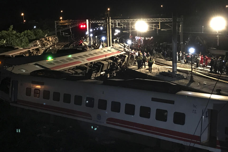 In this Oct. 21, 2018, photo, rescue workers gather at the site of a train derailment in Yilan county northeastern Taiwan. Passengers were killed and injured on Sunday when one of Taiwan's newer, faster trains derailed on a curve along a popular weekend route, officials said. (AP Photo/Johnson Lai, File)