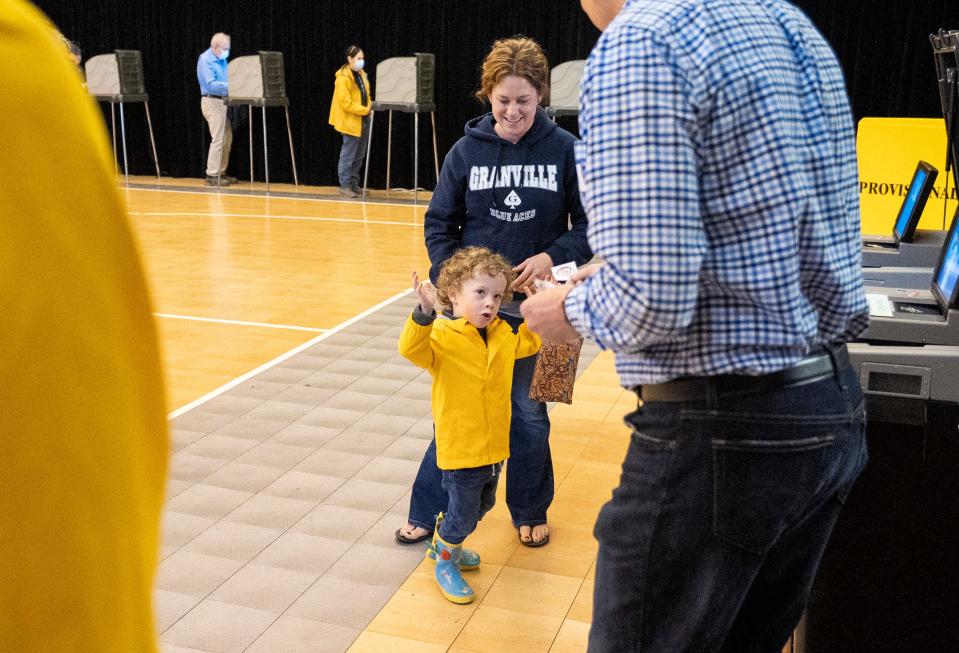Leah Krupp escorts her 3-year-old son, Max, while he asks for a sticker Tuesday from poll worker Mark Morscher at the Bryn Du Fieldhouse in Granville.