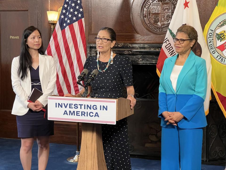 US Secretary of the Interior Deb Haaland speaks at a lectern, flanked by officials Le-Quyen Nguyen (left) and Karen Bass